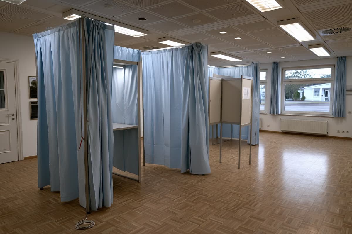 Una cabina de votación vacía con un lápiz atado a una cuerda en un salón comunitario alemán.
