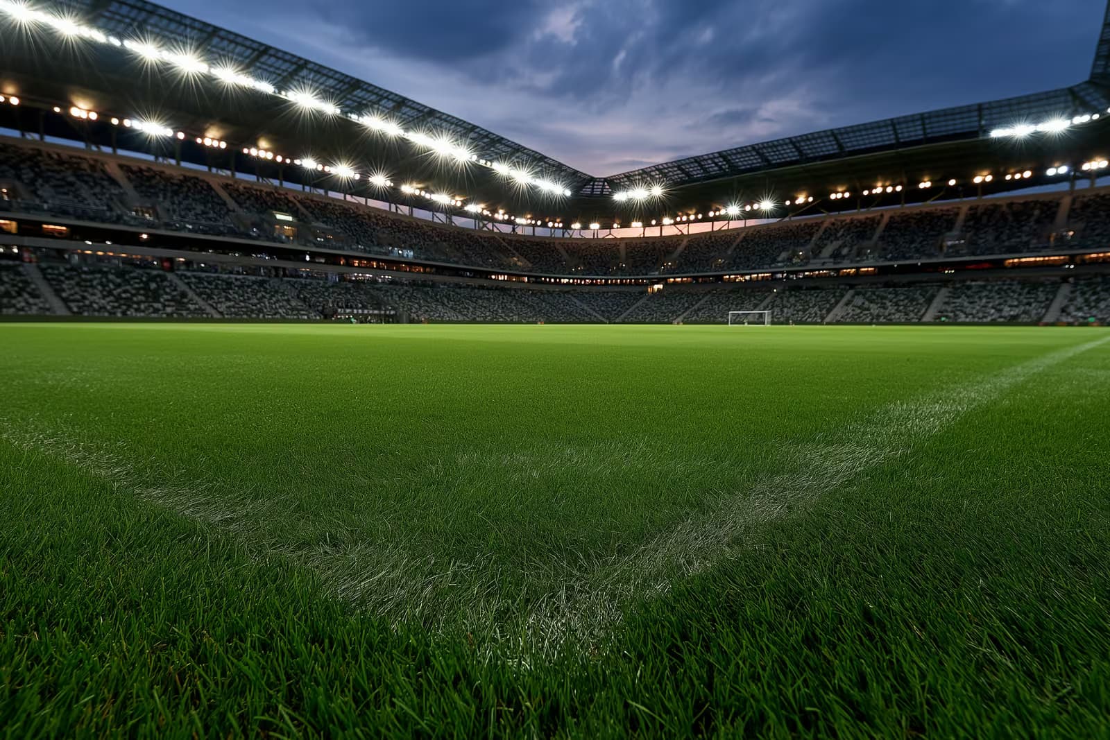 Un estadio de fútbol iluminado al anochecer, antes de un partido nocturno.