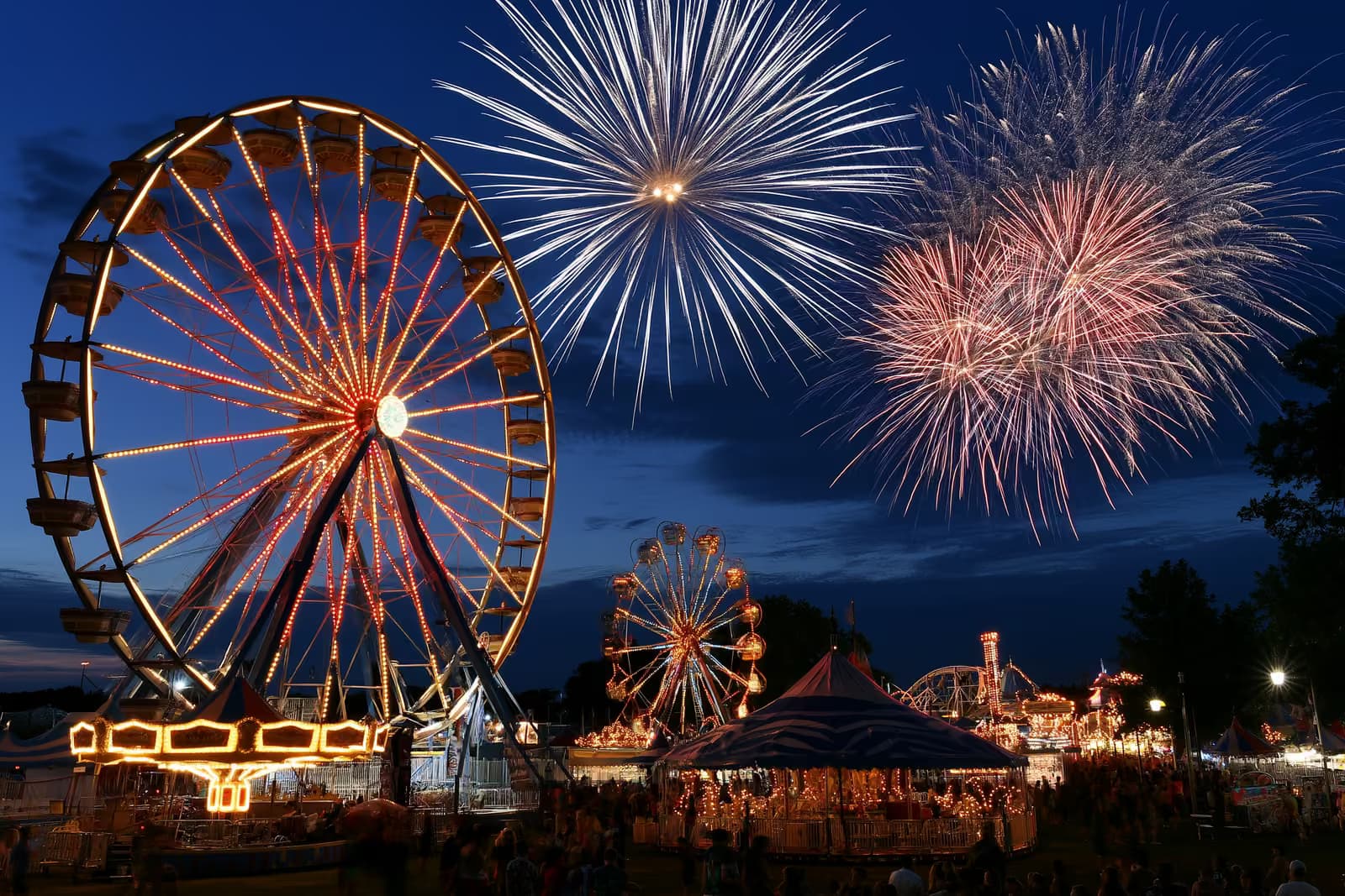 Un parque de atracciones brillantemente iluminado con una gran noria y atracciones al atardecer en el Heiligengeistfeld de Hamburgo.