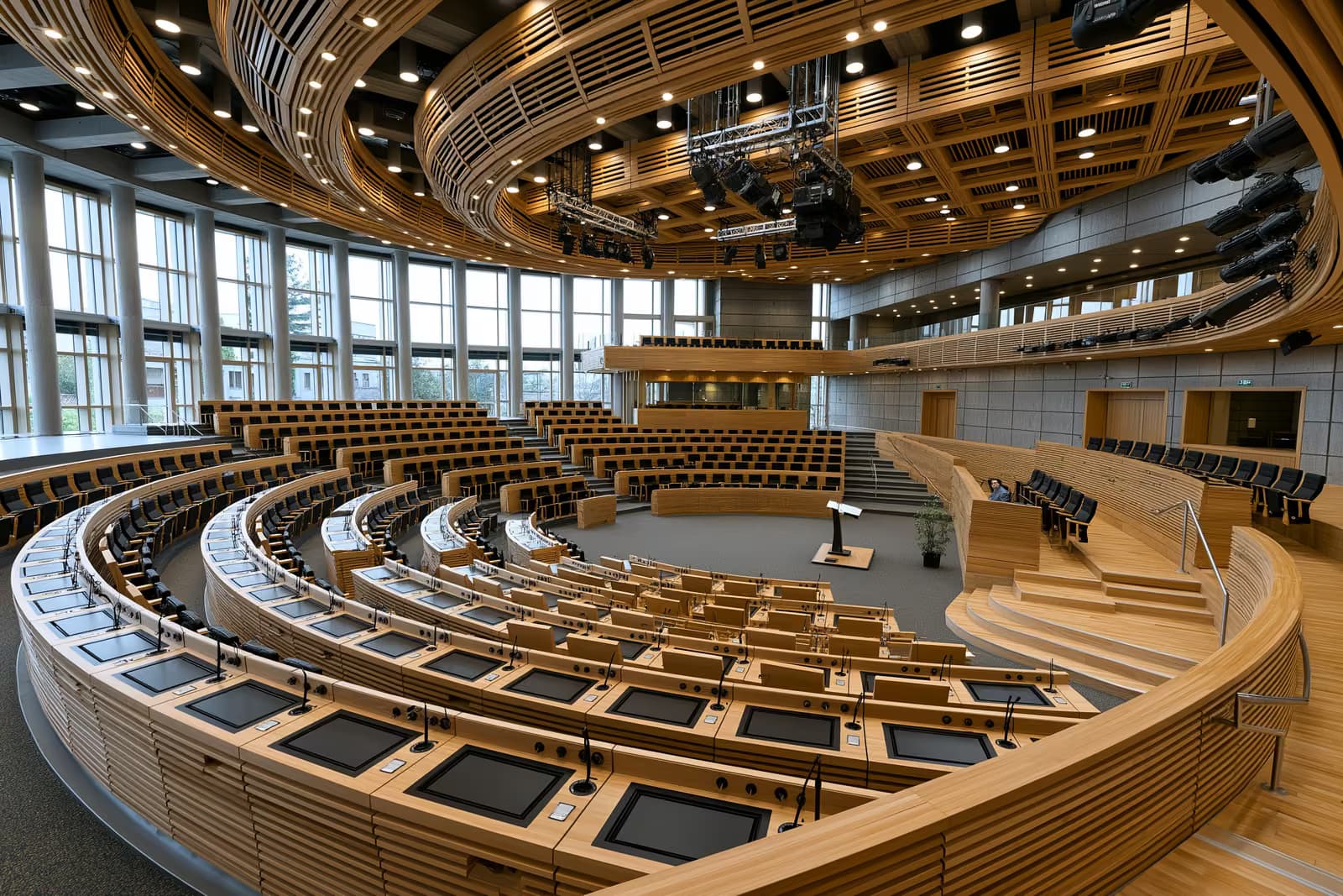 Amplio interior de una sala plenaria vacía del parlamento nacional antes de un debate.