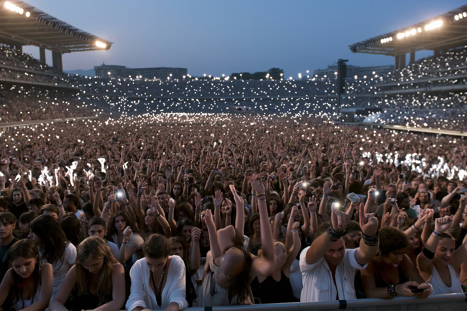 Una gran multitud en un estadio, iluminada por las luces del atardecer, durante un concierto de verano en Múnich.